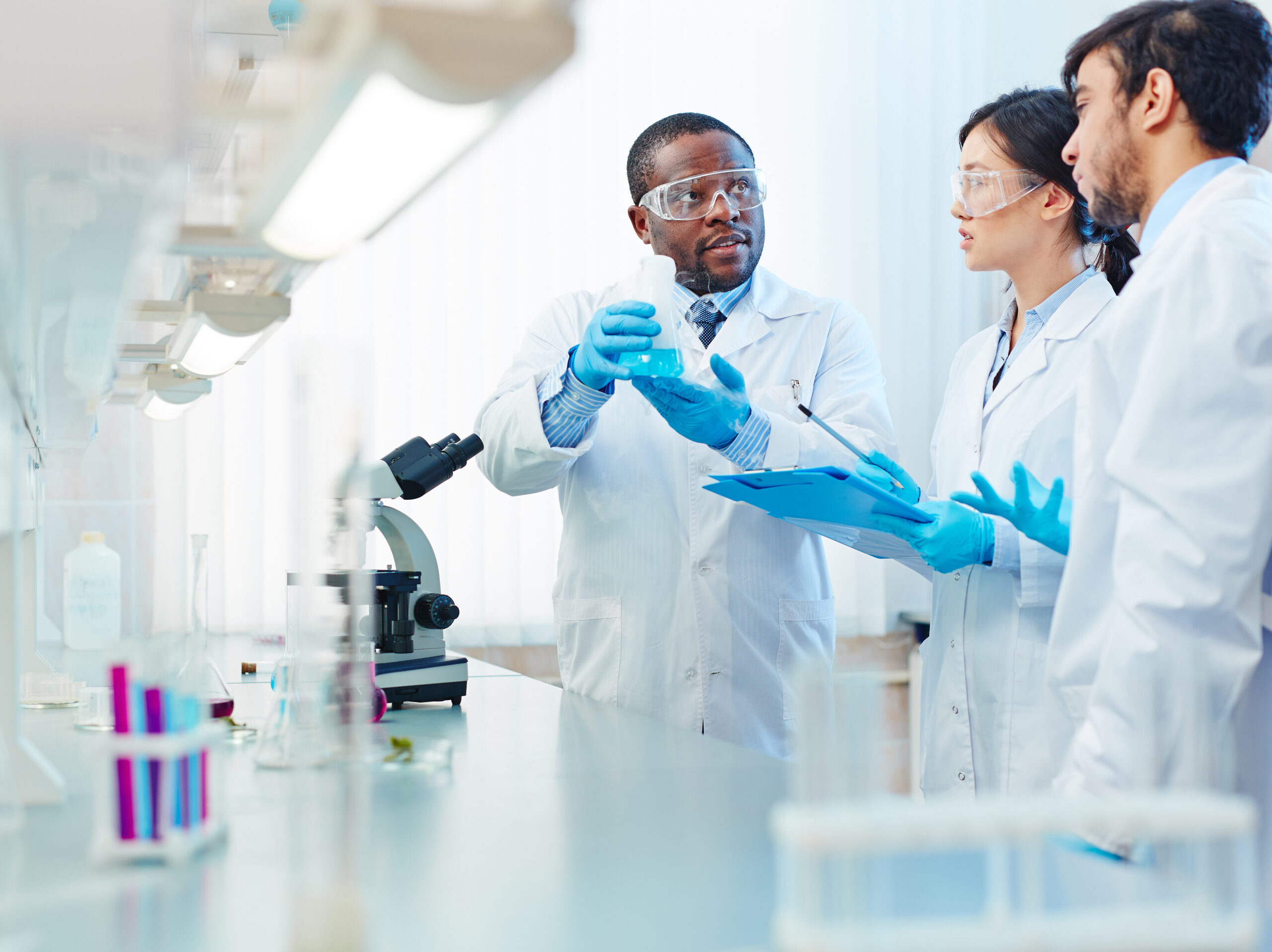 A scientist holding a flask and showing the results his colleagues. 