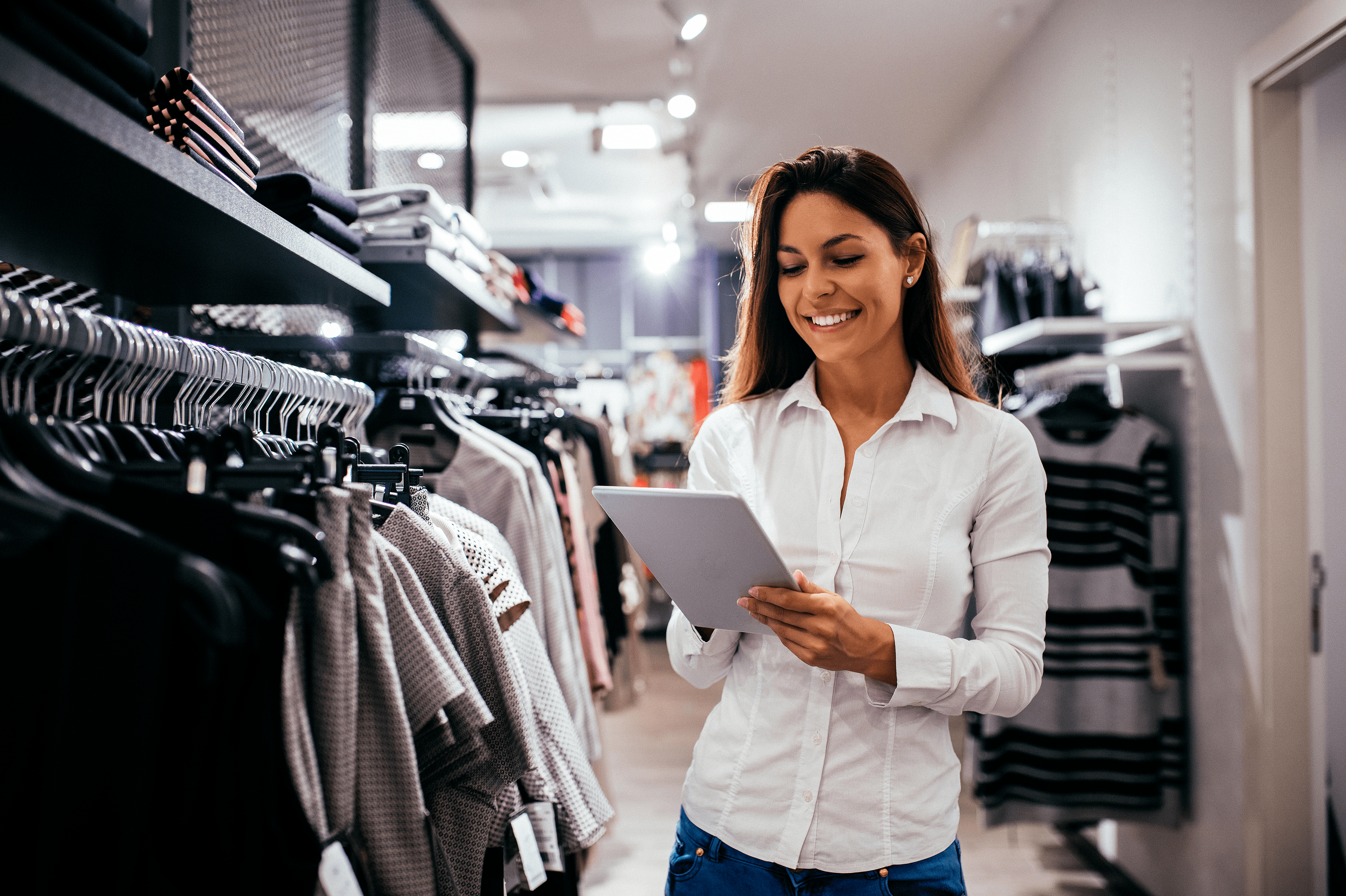 A woman holding a tablet in an apparel store.