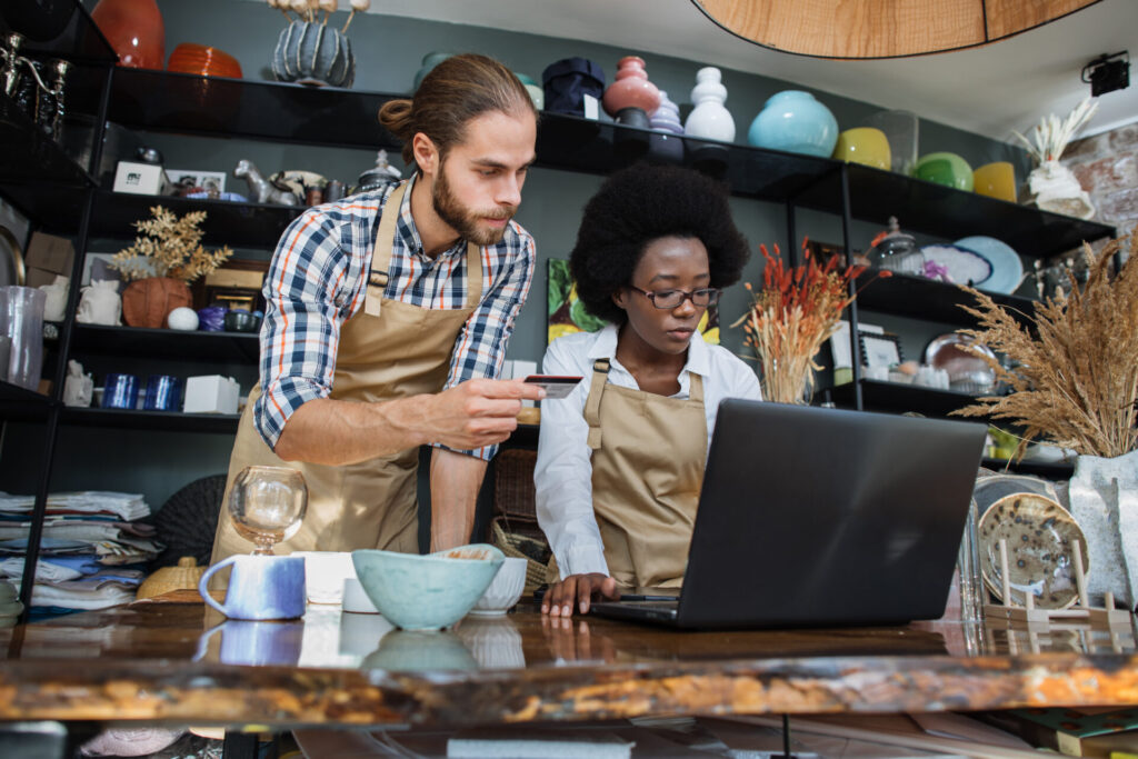 A Man with a credit card in his hand and a woman working on a laptop.