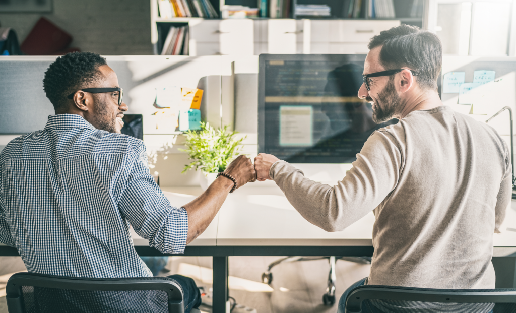 Two friends bumping fists in the office.